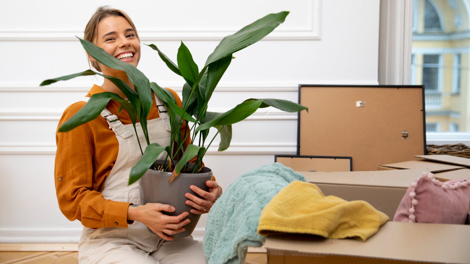 woman holding potted plant in beige pot moving into new home