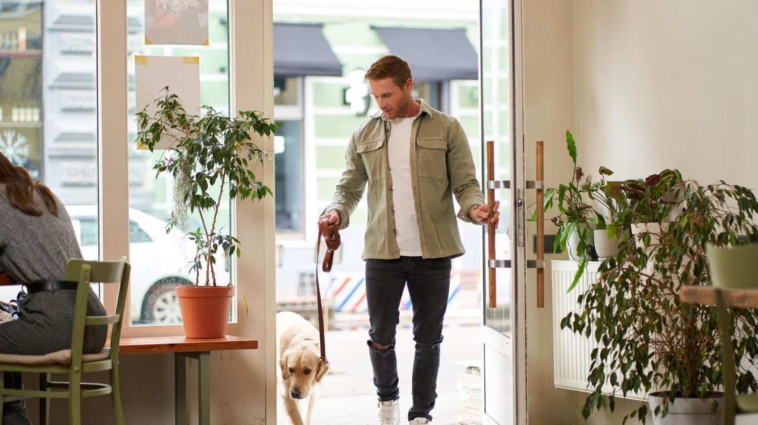 man with dog in leash entering coffee shop with potted plants - Plant Studio