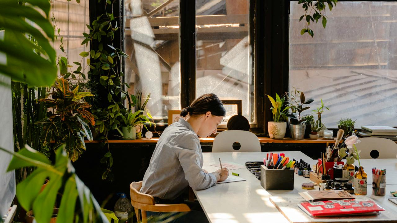 woman working surrounded by lots of plants in office - Plant Studio