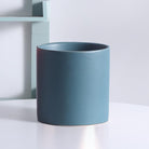 teal cylinder pot placed on top of white table - Plant Studio